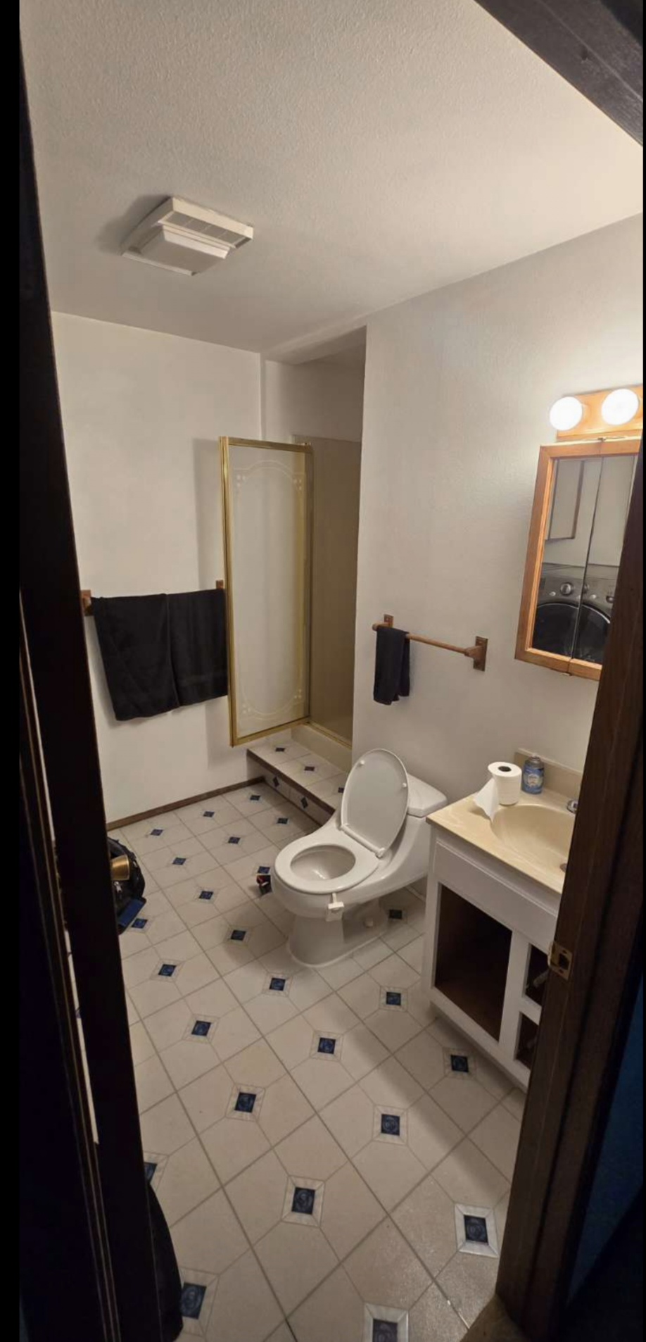 Dated bathroom before remodel — old tile, brass fixtures, oak vanity