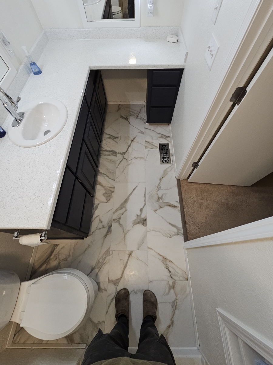 Finished bathroom with marble tile floor and navy vanity