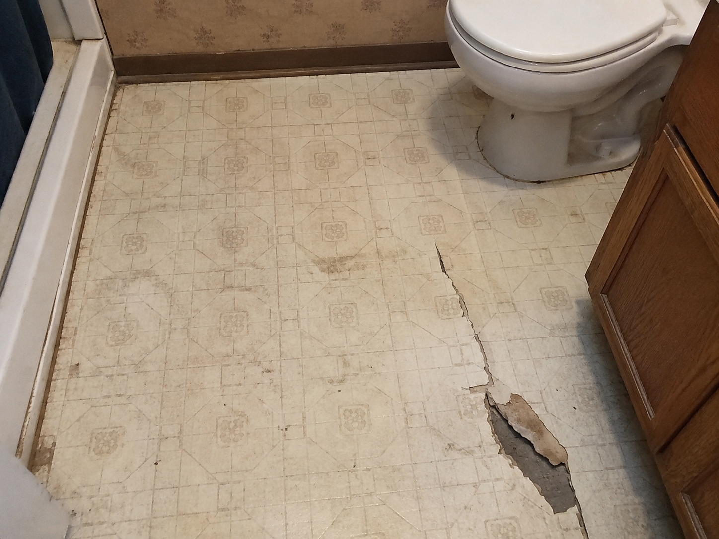 Old cracked vinyl bathroom floor before remodel