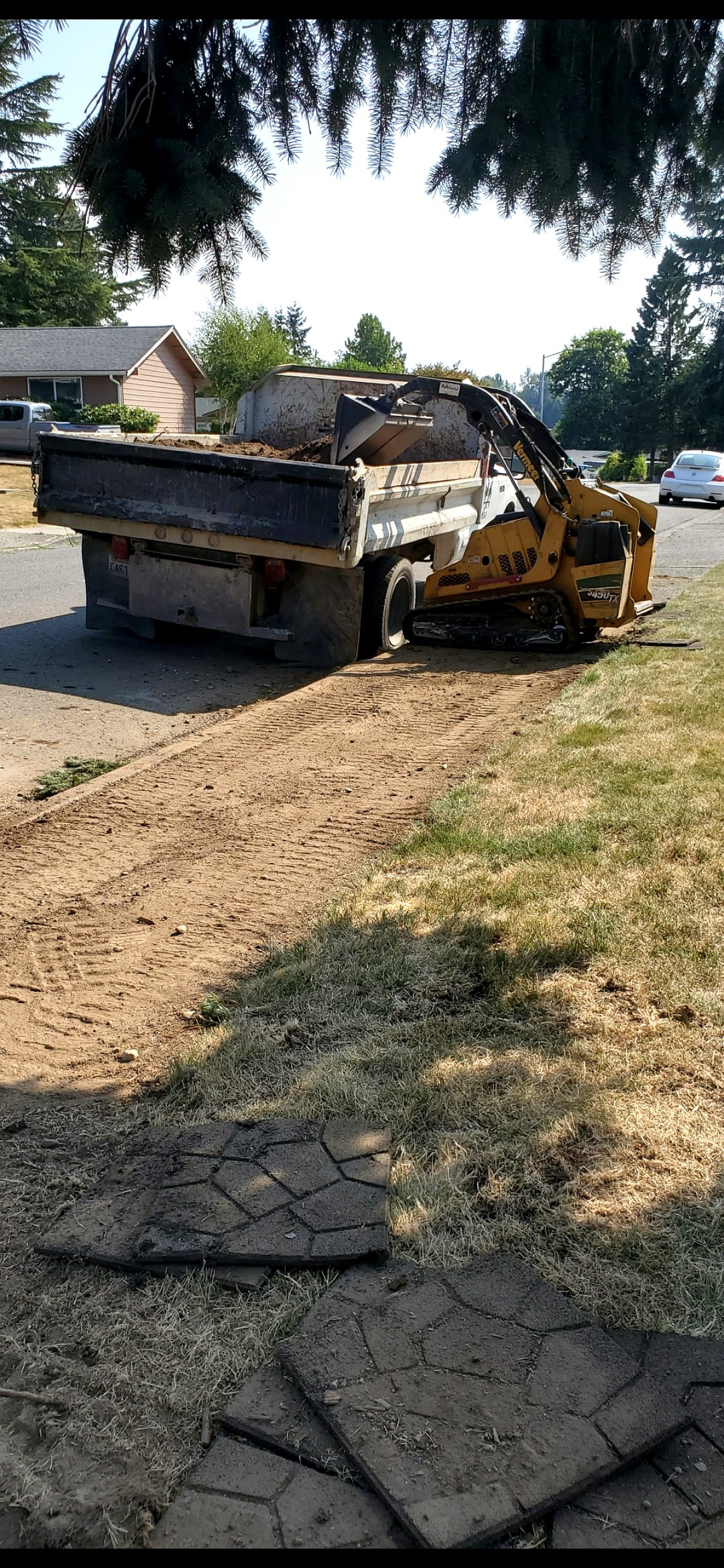 Dump truck being loaded by skid steer on job site