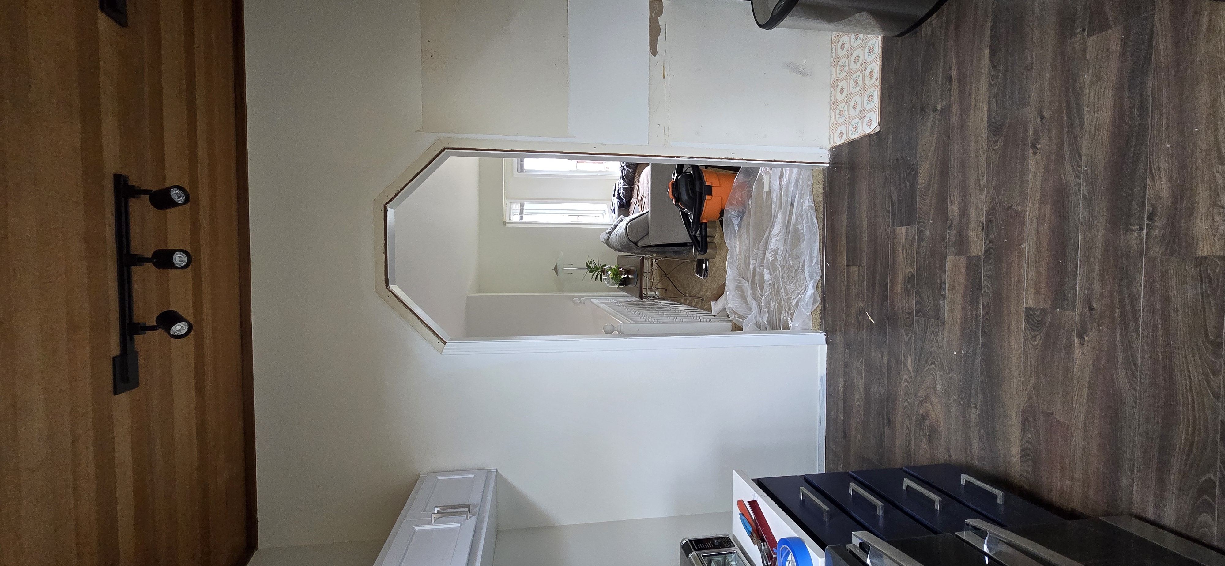 Finished kitchen remodel with white cabinets, stove, and hardwood floor