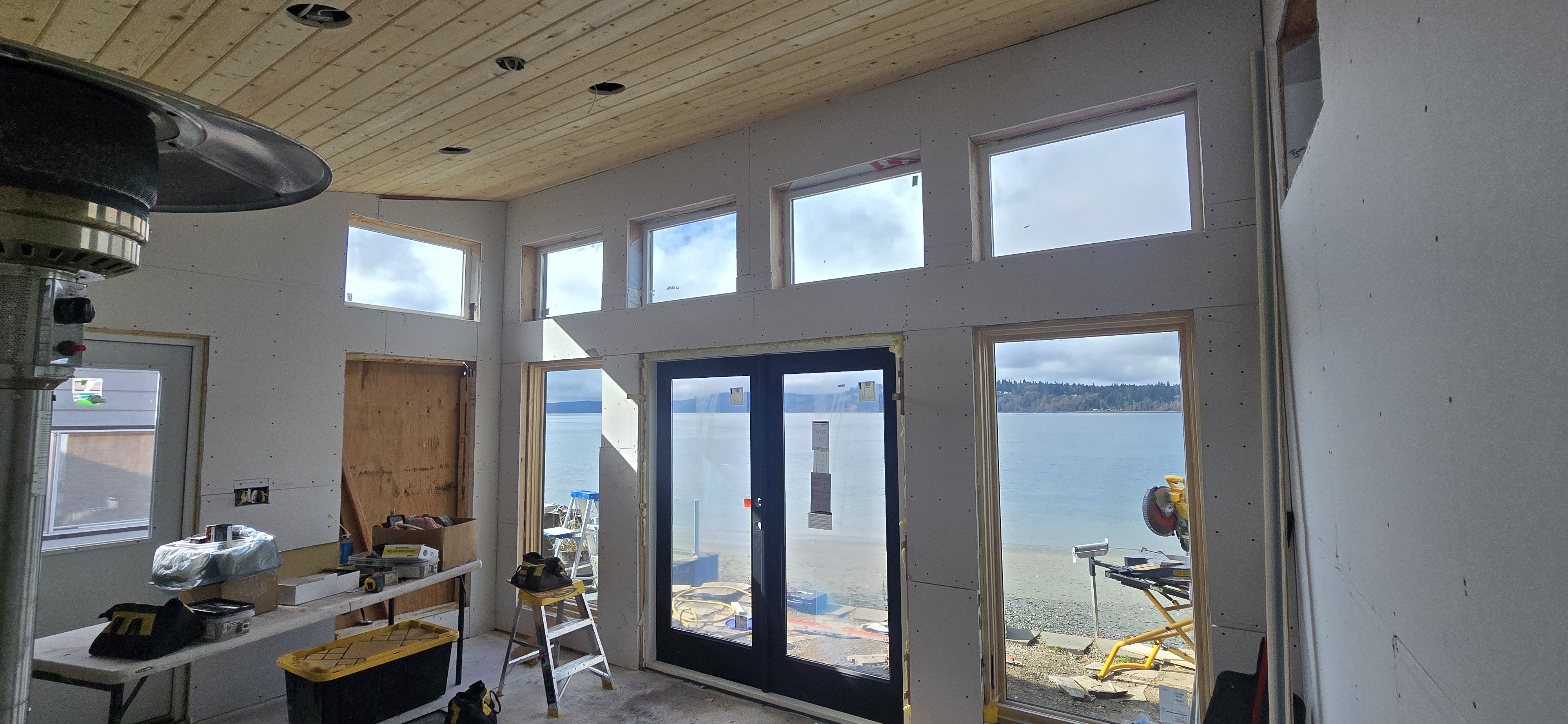 Waterfront room addition with wood plank ceiling, French doors, and transom windows